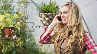 Pretty woman mobile phoning in a green house