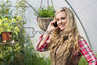 Happy woman mobile phoning in a green house