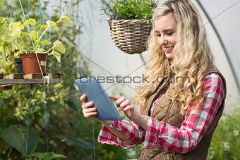 Pretty woman using her tablet in a green house