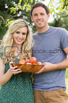 Young couple holding a bowl with apples
