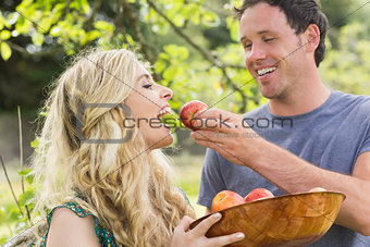 Young man feeding his girlfriend with an apple