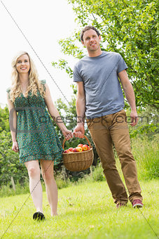 Sweet couple carrying a basket of apples
