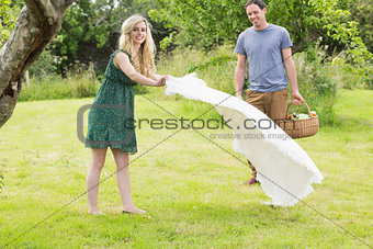 A woman spreading a blanket for a picnic with her boyfriend