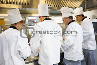 Four chefs working in industrial kitchen
