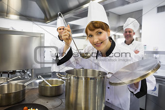 Young female chef tasting a soup