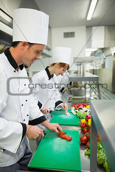 Two young chefs cutting vegetables