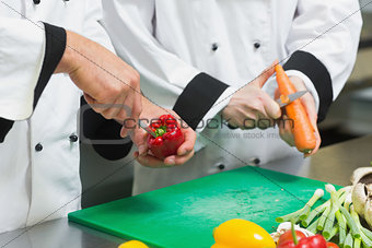 Close up of two chefs cutting vegetables