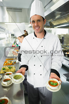 Young male chef presenting two types of soup