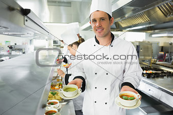 Happy chef presenting two types of soup