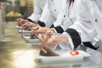 Team of chefs garnishing dessert plates