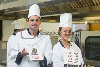Two proud chefs presenting dessert plates