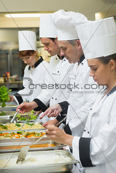 Four chefs working at serving trays