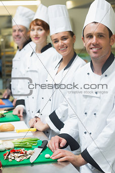 Four chefs standing in a row smiling at the camera