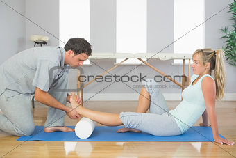 Physiotherapist examining patients foot while sitting on floor