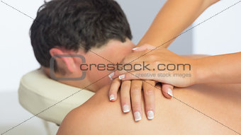 Physiotherapist massaging male patient with hands