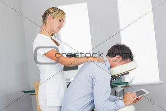 Masseuse massaging clients neck in massage chair