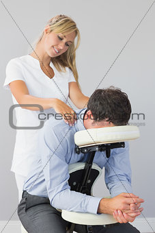 Masseuse treating clients neck in massage chair