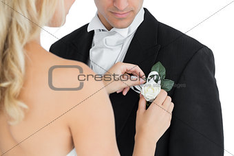Blonde bride pinning a flower on the suit of her husband