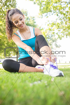 Happy active brunette tying her shoelaces