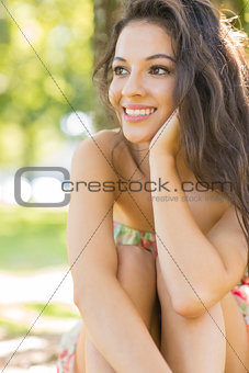 Stylish attractive brunette sitting under a tree