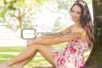 Stylish cute brunette sitting under a tree