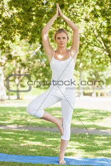 Front view of calm woman in tree yoga pose on an exercise mat