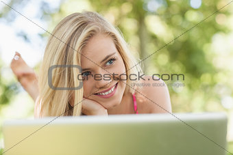 Happy day dreaming woman lying in front of her notebook