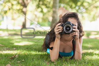 Front view of brunette woman lying on a lawn for taking a picture