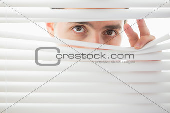 Suspicious male eyes spying through roller blind