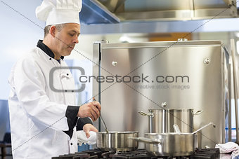 Focused head chef stirring in pot