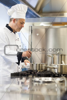 Concentrating head chef stirring in pot