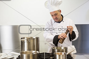 Focused head chef using pepper mill