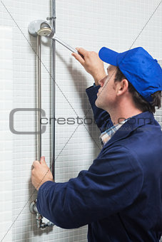 Serious plumber repairing shower head