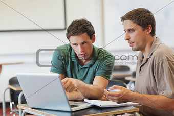 Two concentrated handsome mature students sitting in class