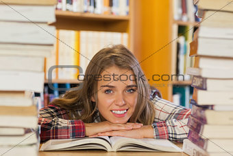 Smiling pretty student studying between piles of books