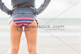 Mid section of a woman in bikini bottom and jacket at beach