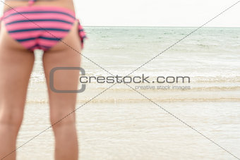 Mid section of a woman in striped bikini bottom at beach