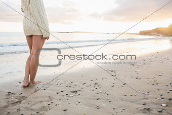 Low section of a woman in sweater standing on beach