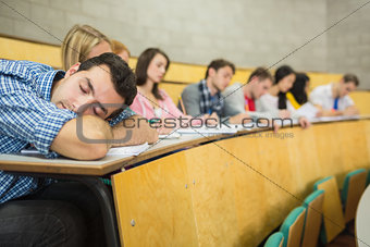 Male sleeping with students in lecture hall