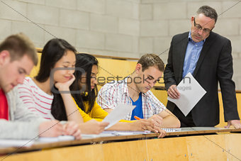 Teacher with students writing notes in lecture hall