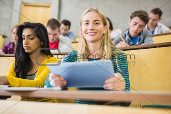 Female holding tablet PC with students at lecture hall