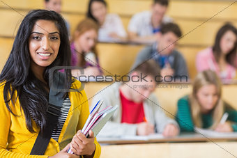 Smiling female with students sitting at the lecture hall