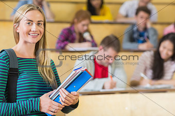 Smiling female with students sitting at the lecture hall