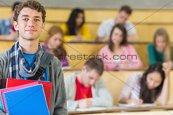 Smiling male with students sitting at lecture hall