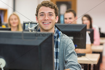 Smiling male student with others in computer room
