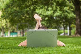 Young woman lying on grass in front of laptop