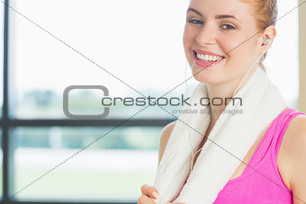 Smiling woman with towel around neck listening to music in fitness studio