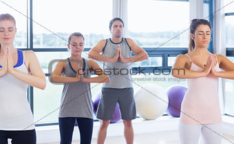 Fitness class and instructor standing in Namaste position