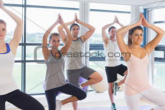 Fitness class and instructor standing in tree pose