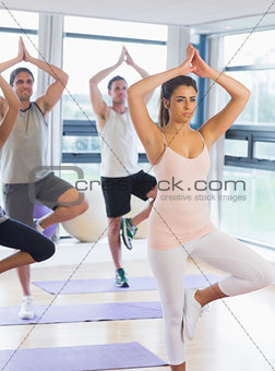 Fitness class and instructor standing in tree pose